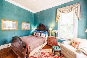 a bedroom with blue walls and a bed and a couch at Belle Oaks Inn in Gonzales