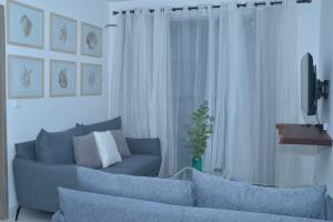 a living room with a blue couch and a television at Kensington Square Luxury Apartment in Flic-en-Flac