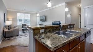 a kitchen with a sink and a living room at Landing - Modern Apartment with Amazing Amenities (ID4410X01) in Lewis Center