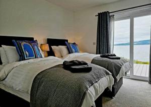 a bedroom with two beds and a large window at Shoreside Villa - immaculate waterfront property in Skelmorlie in Skelmorlie