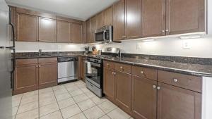 a kitchen with wooden cabinets and stainless steel appliances at Landing - Modern Apartment with Amazing Amenities (ID1316X116) in Bethesda