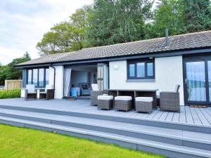 a house with a deck with chairs and a table at Shoreside Villa - immaculate waterfront property in Skelmorlie in Skelmorlie