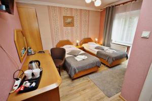 Cette chambre comprend deux lits et un bureau. dans l'établissement Bed&Breakfast Maciejanka, à Kobyla Góra
