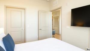 a bedroom with a white bed and a flat screen tv at Landing - Modern Apartment with Amazing Amenities (ID8201X09) in Orlando