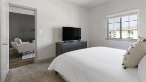 a white bedroom with a bed and a television at Landing - Modern Apartment with Amazing Amenities (ID1215X775) in Burleson