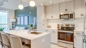 - une cuisine avec des placards blancs et un îlot de cuisine avec un four micro-ondes dans l'établissement Landing - Modern Apartment with Amazing Amenities (ID8310X07), à Salt Lake City