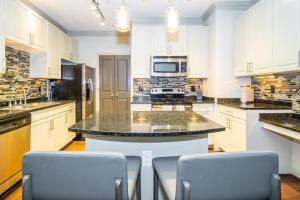 a kitchen with white cabinets and a island with chairs at Landing - Modern Apartment with Amazing Amenities (ID3752) in Atlanta