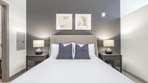ein Schlafzimmer mit einem weißen Bett mit zwei Lampen in der Unterkunft Landing - Modern Apartment with Amazing Amenities (ID1208X248) in Charlotte