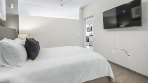 ein weißes Schlafzimmer mit einem Bett und einem Flachbild-TV in der Unterkunft Landing - Modern Apartment with Amazing Amenities (ID1208X248) in Charlotte