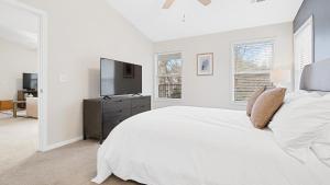 ein weißes Schlafzimmer mit einem großen Bett und einem TV in der Unterkunft Landing - Modern Apartment with Amazing Amenities (ID8245X00) in Winston-Salem