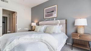 una camera da letto con un grande letto bianco con due lampade di Landing - Modern Apartment with Amazing Amenities (ID7779X23) ad Austin