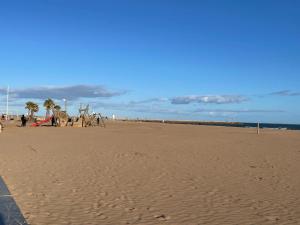 a sandy beach with palm trees and a playground at Vos vacances à la mer in Valras-Plage +3 photos