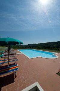 a swimming pool with chairs and an umbrella at Podere Chiaromonte in Palaia