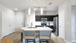 een keuken met een wastafel en een aanrecht met stoelen bij Landing - Modern Apartment with Amazing Amenities (ID3561X40) in Austin