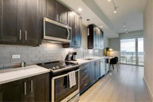 una cocina con armarios de madera y una gran ventana en Landing - Modern Apartment with Amazing Amenities (ID4772X11) en Dallas