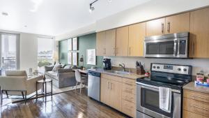 cocina con electrodomésticos de acero inoxidable y sala de estar. en Landing Modern Apartment with Amazing Amenities (ID8925X56), en Tacoma