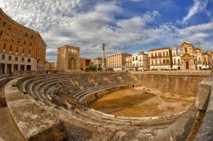 ein antikes Amphitheater in einer Stadt mit Gebäuden in der Unterkunft Mammasisi Rooms in Lecce