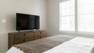 ein Schlafzimmer mit einem Flachbild-TV auf einer Kommode in der Unterkunft Landing - Modern Apartment with Amazing Amenities (ID2396X34) in Baton Rouge