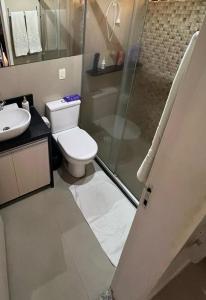 a bathroom with a toilet and a glass shower at Gavoa Resort Flat - Mar Doce Lar in Igarassu