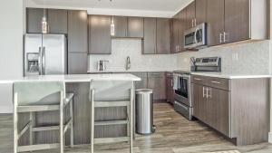 uma cozinha com armários de madeira e electrodomésticos de aço inoxidável em Landing - Modern Apartment with Amazing Amenities (ID5507X06) em Denver