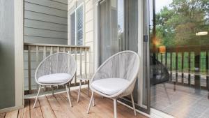 Duas cadeiras brancas sentadas num alpendre com uma janela em Landing - Modern Apartment with Amazing Amenities (ID5166X12) em Denver