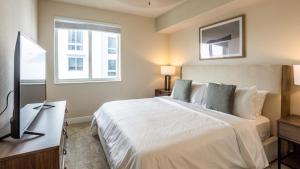 een slaapkamer met een groot wit bed en een televisie bij Landing - Modern Apartment with Amazing Amenities (ID7823X09) in Miami