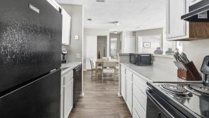 een keuken met een zwarte koelkast en witte kasten bij Landing - Modern Apartment with Amazing Amenities (ID1182X728) in College Park