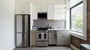 cocina con armarios blancos y nevera de acero inoxidable en Landing - Modern Apartment with Amazing Amenities (ID5790X34), en Birmingham