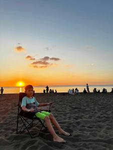 a young boy sitting in a chair on the beach at Purple Guesthouse in Nasugbu