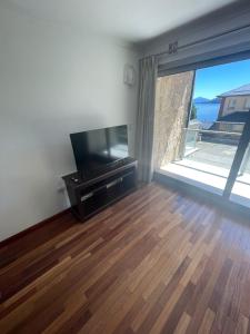 a living room with a flat screen tv and a wooden floor at Duplex Quinta Luna in San Carlos de Bariloche