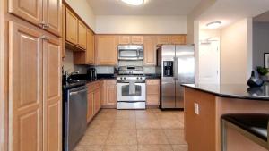 una cocina con armarios de madera y electrodomésticos de acero inoxidable en Landing - Modern Apartment with Amazing Amenities (ID8572X47), en Las Vegas