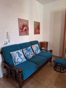 eine blaue Couch in einem Wohnzimmer mit zwei Gemälden in der Unterkunft Casa di Lu in SantʼAntìoco