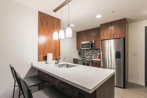 a kitchen with wooden cabinets and a stainless steel refrigerator at Landing - Modern Apartment with Amazing Amenities (ID2652) in Los Angeles