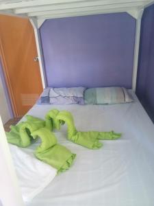 a bed with some green towels on it at Purple Guesthouse in Nasugbu