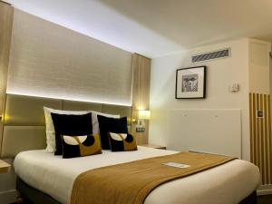Habitación de hotel con cama grande con almohadas amarillas y negras en Kyriad Beaune, en Beaune