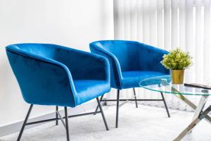 - deux chaises bleues et une table en verre dans une pièce dans l'établissement Modern Apartment - Twin Beds - Free Netflix & Wifi - Parking - Top Rated - 7OC, à Brierley Hill