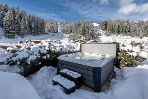 un bain à remous dans la neige avec des arbres enneigés dans l'établissement Postresidenz am See, à Arosa