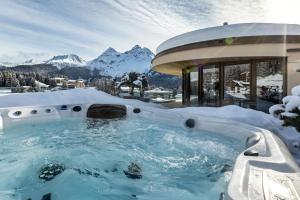 a hot tub covered in snow with mountains in the background at Postresidenz am See in Arosa