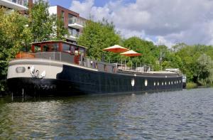 イーペルにあるBed in Boatの船が建物の隣の水上に停泊