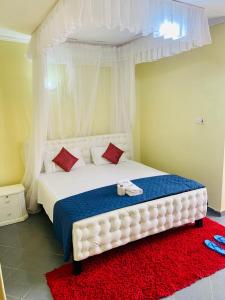 Schlafzimmer mit einem großen weißen Bett und einem roten Teppich in der Unterkunft Yonga Apartment in Kisumu