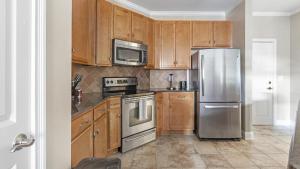 a kitchen with wooden cabinets and stainless steel appliances at Landing - Modern Apartment with Amazing Amenities (ID1285X345) in Greensboro
