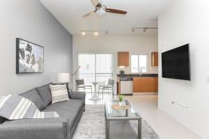 a living room with a couch and a table and a kitchen at Landing - Modern Apartment with Amazing Amenities (ID2654) in Tampa