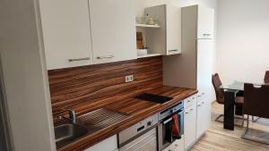 a kitchen with white cabinets and a wooden counter top at Große Monteurwohnung André bei Würzburg bis 6 Personen mit eigenen gratis Parklätzen und Grill und WLAN 3x Schlafzimmer - nur Einzelbetten in Veitshöchheim
