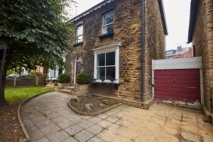 a brick house with a garage and a red garage door at Cosy, Stylish, Leafy And Homely in Sheffield
