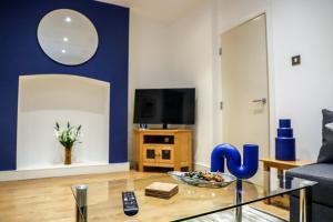a living room with a glass table and a blue wall at New- Modern 2br Apt Wifi Sleep5 City Centre in Sheffield