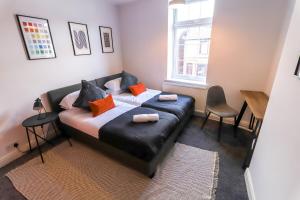 a bedroom with a black leather bed with orange pillows at Beautiful 3 Bedroom House - Sleeps 5 Free Parking in Longley