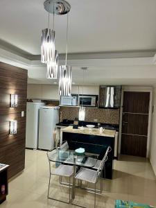 a kitchen with a glass table with chairs and appliances at Gavoa Resort Flat - Mar Doce Lar in Igarassu