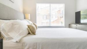 - un lit blanc avec des oreillers blancs et une télévision dans l'établissement Landing - Modern Apartment with Amazing Amenities (ID9398X92), à Lewisville