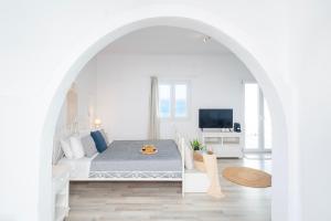 a white bedroom with a bed and a living room at With-inn Mykonos Suites in Tourlos