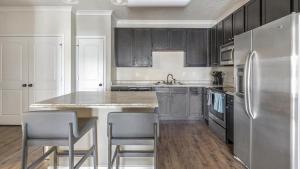 a kitchen with a stainless steel refrigerator and gray cabinets at Landing - Modern Apartment with Amazing Amenities (ID7367X45) in Jacksonville